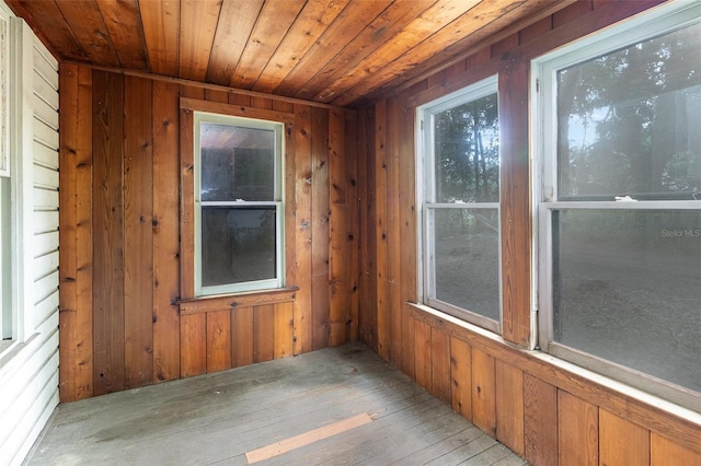 unfurnished room with wooden walls, wooden ceiling, and light wood-type flooring