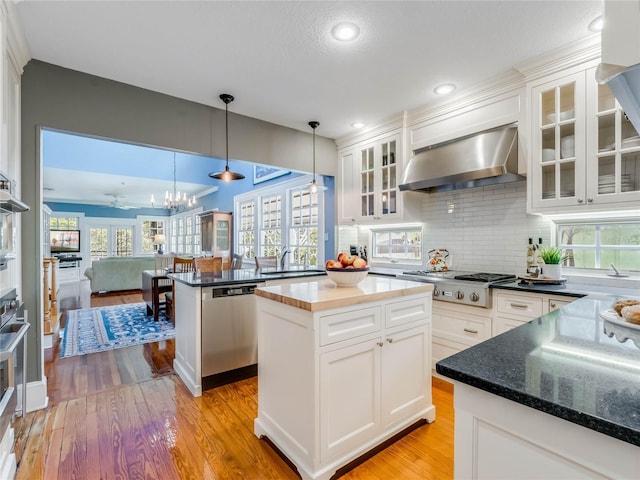 811 Laurel Ave, Orlando, FL 32803 - kitchen with wall chimney exhaust hood, appliances with stainless steel finishes, light wood-type flooring, a sink, and white cabinets