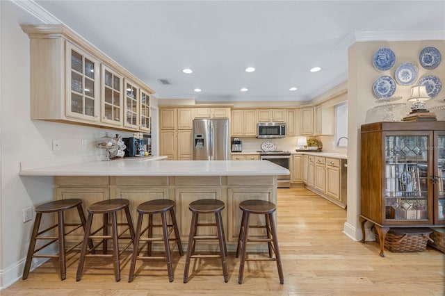 3015 Dawley Ave, Orlando, FL 32806 - kitchen with stainless steel appliances, a peninsula, crown molding, a breakfast bar, and glass insert cabinets