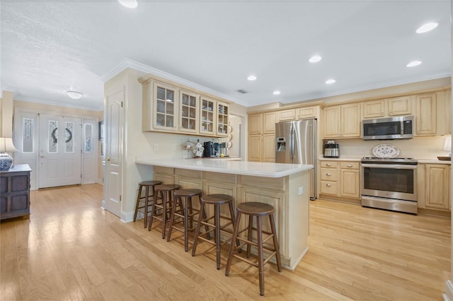 3015 Dawley Ave, Orlando, FL 32806 - kitchen with stainless steel appliances, ornamental molding, a breakfast bar area, a peninsula, and glass insert cabinets