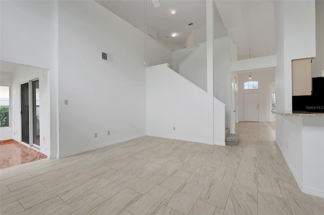 1517 Abberton Dr, Orlando, FL 32837 - unfurnished living room with visible vents, a wealth of natural light, a high ceiling, and stairs