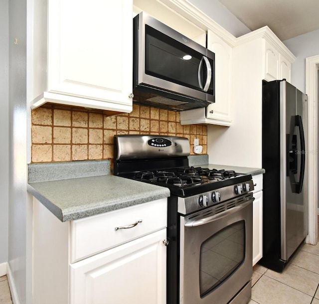 kitchen with white cabinets, appliances with stainless steel finishes, decorative backsplash, and light tile patterned floors