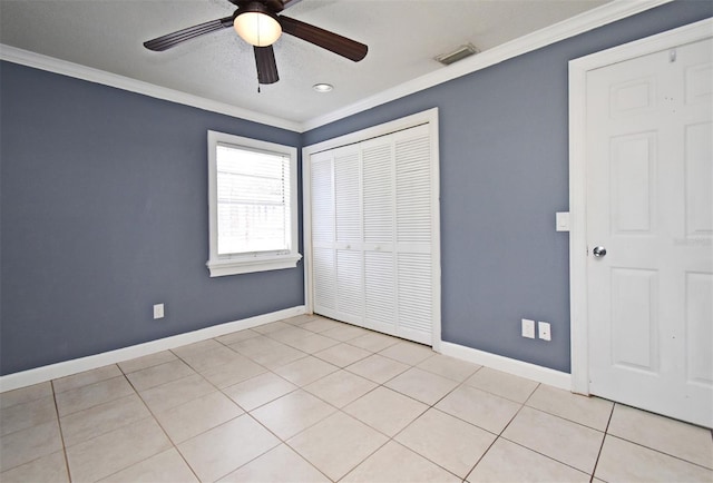 unfurnished bedroom featuring a closet, ornamental molding, visible vents, light tile patterned flooring, and baseboards