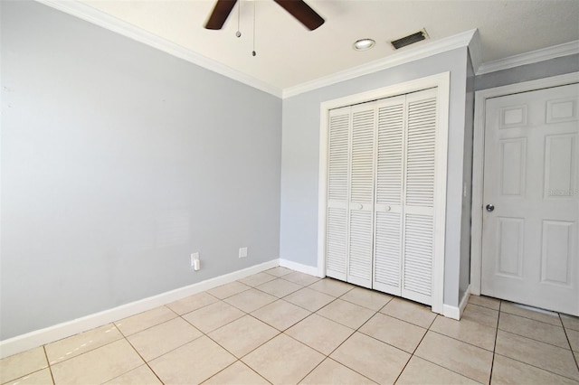 unfurnished bedroom featuring light tile patterned floors, baseboards, a closet, visible vents, and crown molding