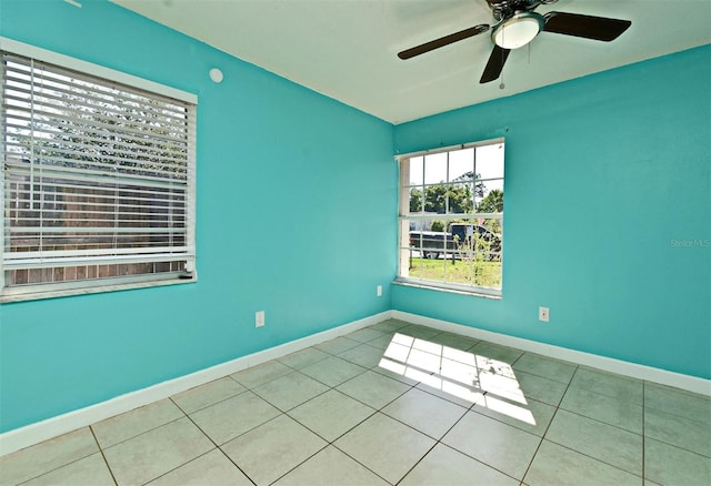 tiled empty room with baseboards and ceiling fan