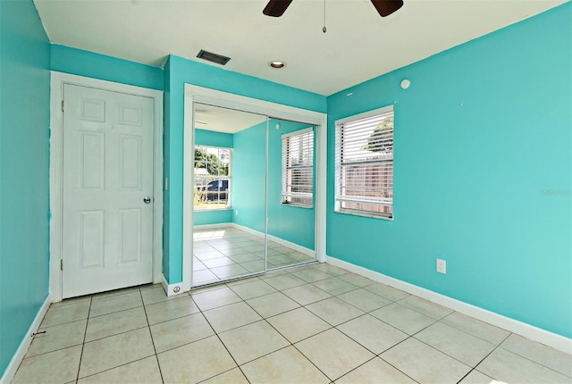 unfurnished bedroom featuring light tile patterned floors, visible vents, multiple windows, and baseboards