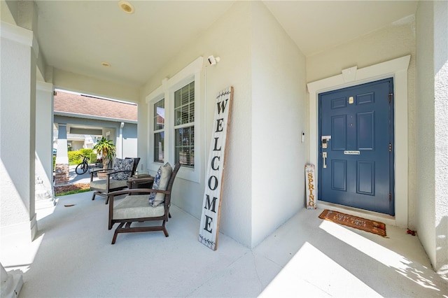 view of exterior entry featuring a porch and stucco siding