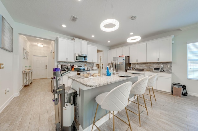 kitchen featuring visible vents, baseboards, appliances with stainless steel finishes, light wood-style floors, and decorative backsplash