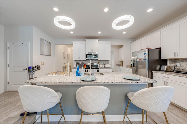 kitchen featuring decorative backsplash, light wood-style flooring, a sink, and appliances with stainless steel finishes
