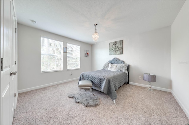 carpeted bedroom with a notable chandelier and baseboards