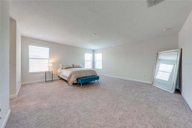 bedroom with light carpet, visible vents, baseboards, and a textured ceiling