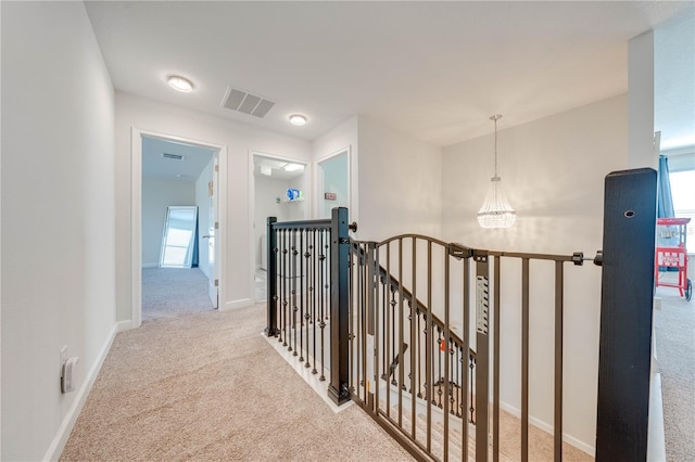 hallway featuring visible vents, an upstairs landing, carpet flooring, and a chandelier