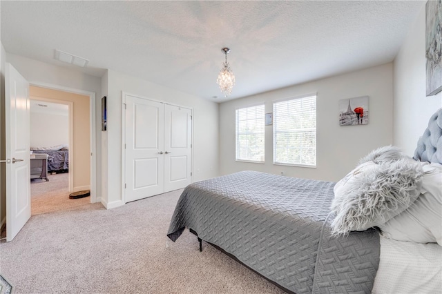 carpeted bedroom featuring a chandelier, visible vents, a closet, and baseboards