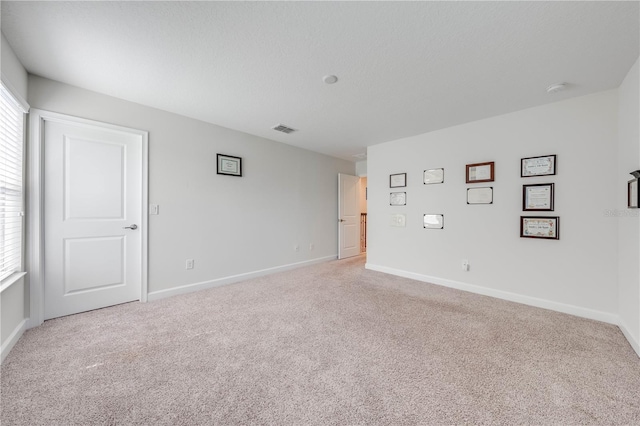 empty room with visible vents, baseboards, and light colored carpet