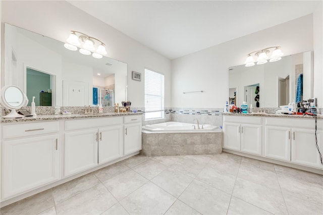full bath featuring two vanities, a sink, a stall shower, tile patterned floors, and a garden tub