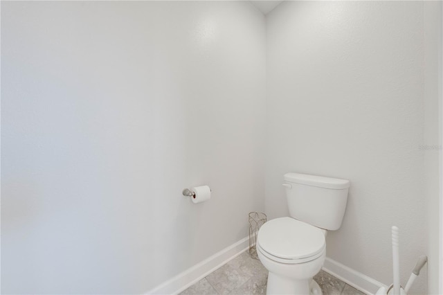 bathroom with toilet, baseboards, and tile patterned flooring