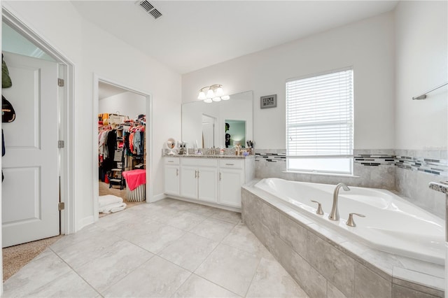 full bathroom featuring visible vents, a bath, a spacious closet, vanity, and tile patterned flooring