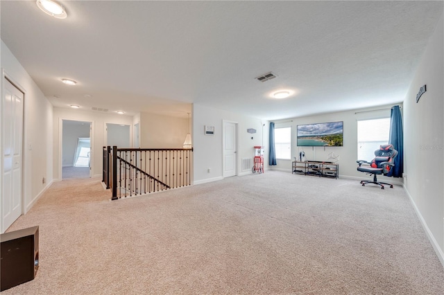 living area with carpet, visible vents, an upstairs landing, and baseboards
