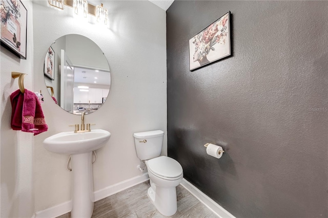 bathroom featuring baseboards, toilet, and wood finished floors