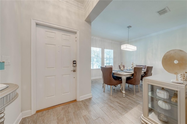 entrance foyer with crown molding, visible vents, baseboards, and light wood-style flooring