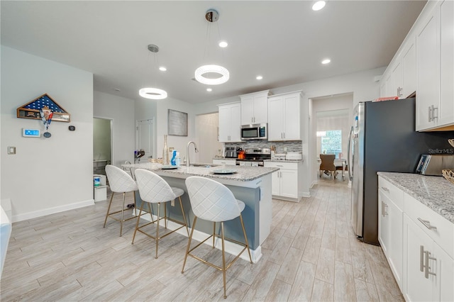 kitchen featuring light wood-type flooring, a sink, white cabinetry, and appliances with stainless steel finishes
