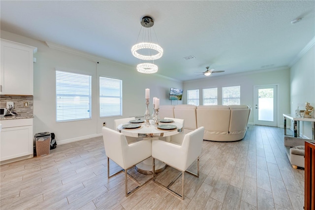 dining space with crown molding, ceiling fan with notable chandelier, light wood finished floors, and visible vents