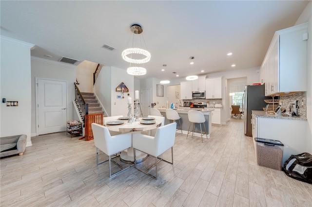 dining area with a chandelier, stairs, visible vents, and crown molding