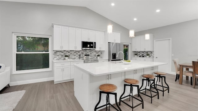 1027 Dees Dr, Oviedo, FL 32765 - kitchen featuring stainless steel appliances, a breakfast bar area, a center island with sink, light countertops, and white cabinets
