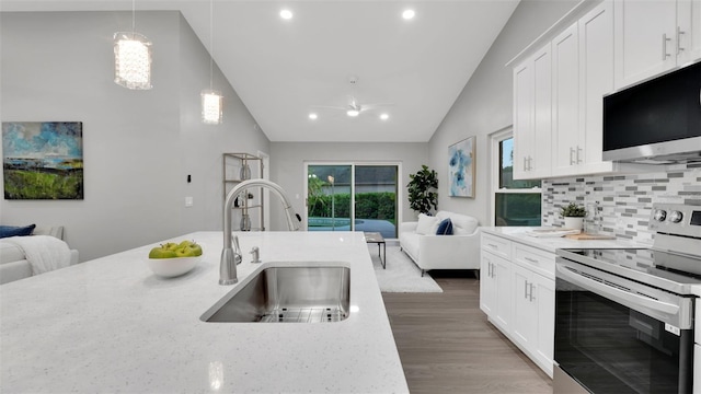 1027 Dees Dr, Oviedo, FL 32765 - kitchen featuring stainless steel appliances, open floor plan, decorative backsplash, white cabinetry, and high vaulted ceiling