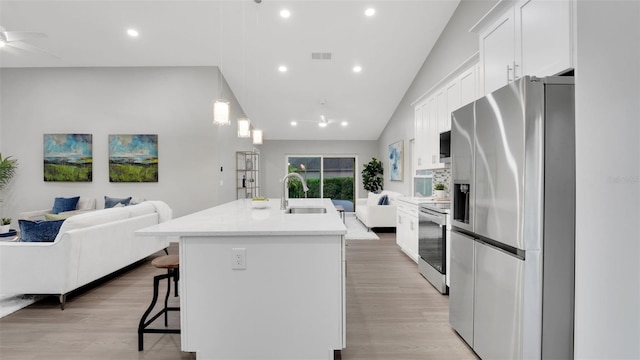 1027 Dees Dr, Oviedo, FL 32765 - kitchen featuring appliances with stainless steel finishes, open floor plan, a kitchen island with sink, a breakfast bar, and white cabinetry