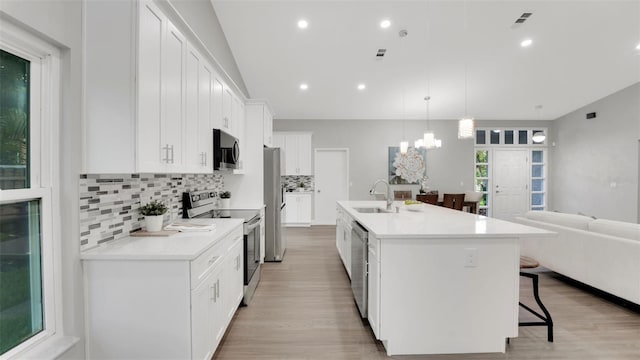 1027 Dees Dr, Oviedo, FL 32765 - kitchen with appliances with stainless steel finishes, a kitchen breakfast bar, backsplash, light wood-style flooring, and a chandelier