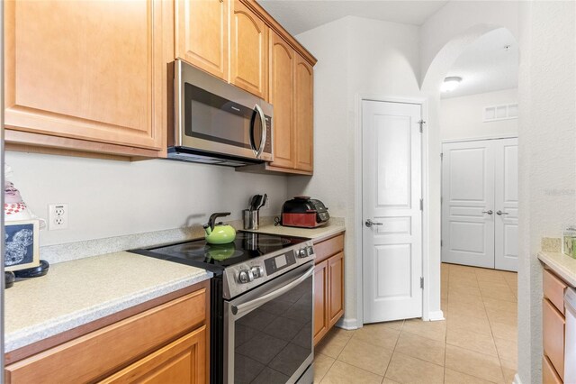 8296 Portofino Dr Unit 405, Davenport, FL 33896 - kitchen with light tile patterned floors, visible vents, arched walkways, light countertops, and appliances with stainless steel finishes