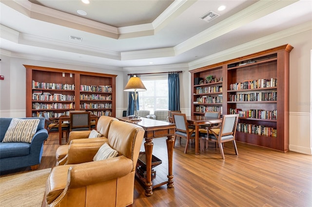 8296 Portofino Dr Unit 405, Davenport, FL 33896 - living area featuring a tray ceiling, wood finished floors, visible vents, and bookshelves