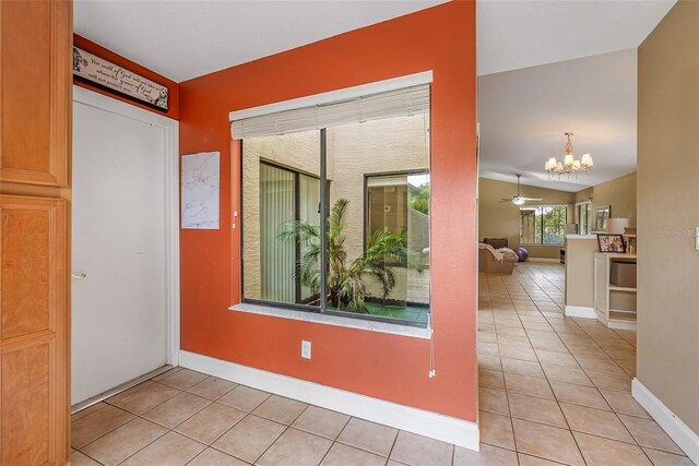 empty room featuring light tile patterned floors, baseboards, an inviting chandelier, and lofted ceiling
