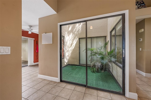 doorway to outside with tile patterned flooring, baseboards, and a ceiling fan