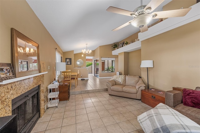 living area with ceiling fan with notable chandelier, light tile patterned flooring, a fireplace, and lofted ceiling