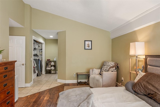 bedroom with light wood-type flooring, a closet, a spacious closet, vaulted ceiling, and baseboards