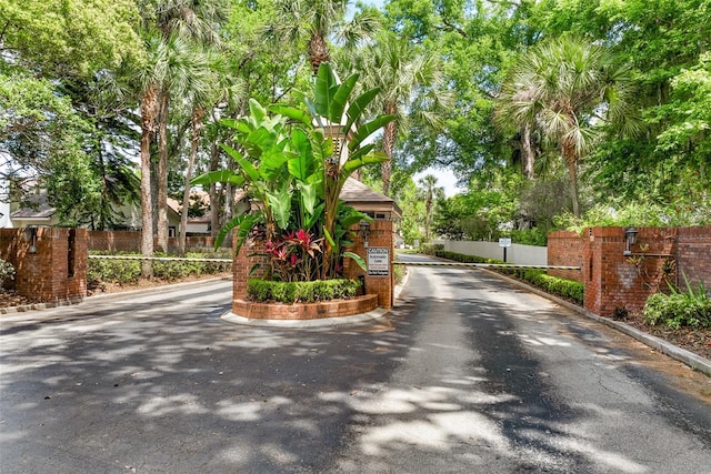 view of street featuring a gated entry and curbs