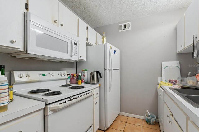 3921 SW 34th St Unit 102, Gainesville, FL 32608 - kitchen featuring white appliances, white cabinets, light countertops, light tile patterned floors, and a sink