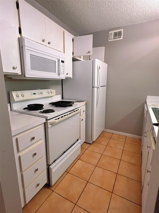 3921 SW 34th St Unit 102, Gainesville, FL 32608 - kitchen featuring white appliances, light tile patterned flooring, a textured ceiling, white cabinets, and light countertops