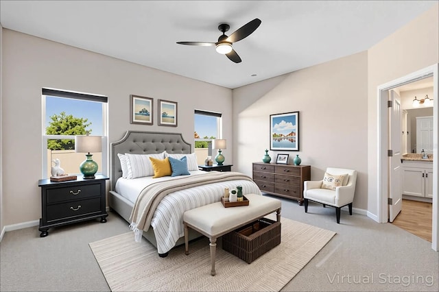 bedroom with baseboards, light colored carpet, ceiling fan, and ensuite bath