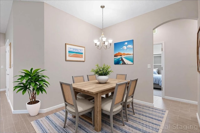 dining room featuring arched walkways, baseboards, and a notable chandelier