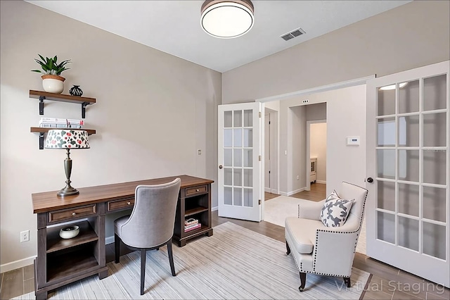 office space with baseboards, visible vents, french doors, and wood finished floors