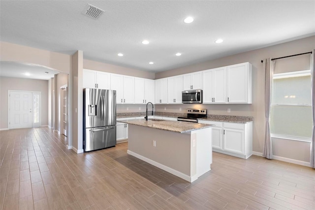 kitchen featuring visible vents, a sink, baseboards, arched walkways, and appliances with stainless steel finishes