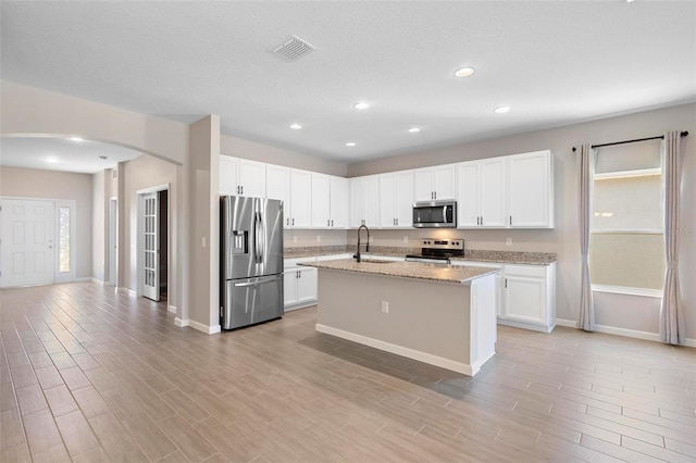 kitchen with arched walkways, baseboards, appliances with stainless steel finishes, and white cabinetry