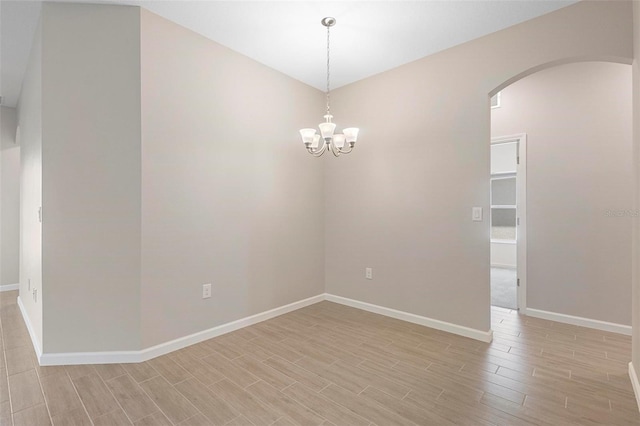 empty room featuring arched walkways, baseboards, an inviting chandelier, and wood tiled floor
