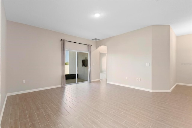 unfurnished bedroom featuring arched walkways, baseboards, light wood-type flooring, and visible vents