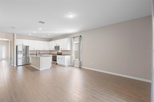 kitchen with visible vents, a sink, baseboards, open floor plan, and stainless steel appliances
