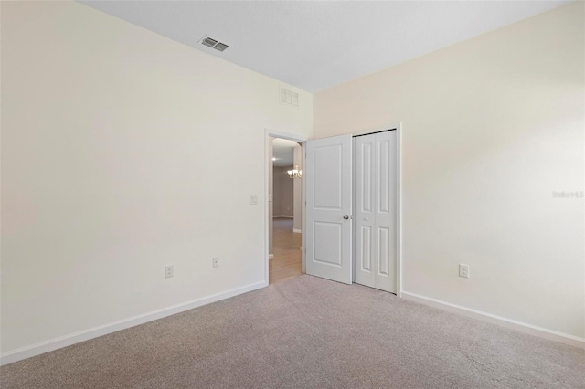 unfurnished bedroom featuring baseboards, light carpet, and visible vents
