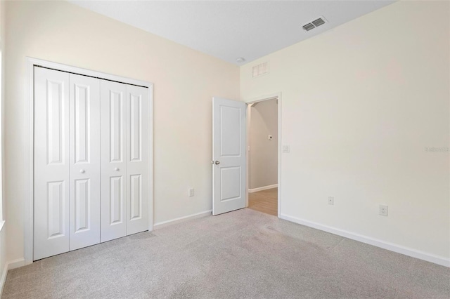 unfurnished bedroom featuring visible vents, carpet, baseboards, and a closet